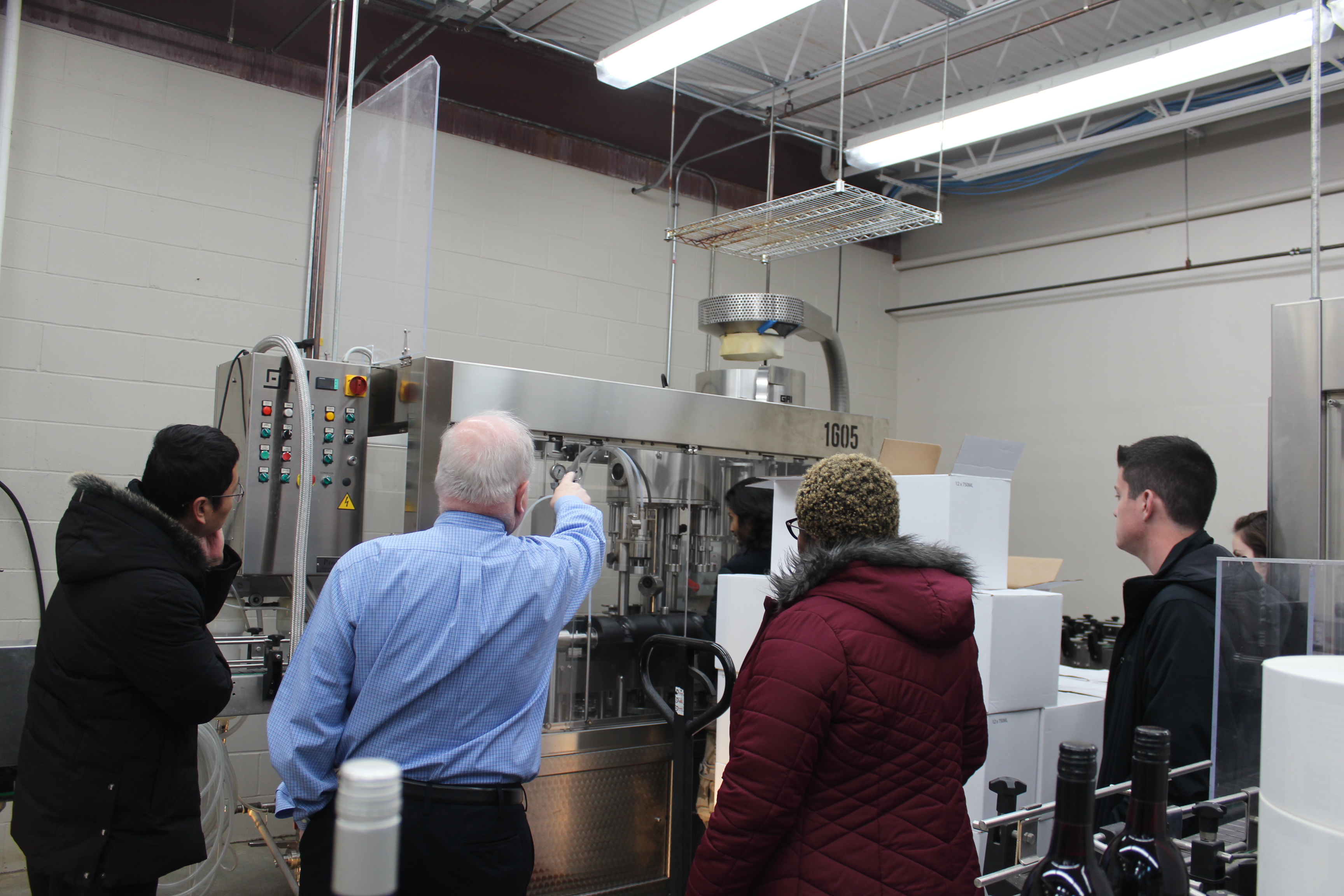 Three international students being shown a production machine by a local manufacturing company